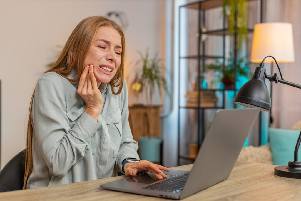 Person holding jaw in pain, possibly from a cracked tooth, searching for natural remedies or solutions